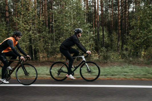 Cyclist riding along a road on a aerodynamic road bike with another cyclist drafting behind him